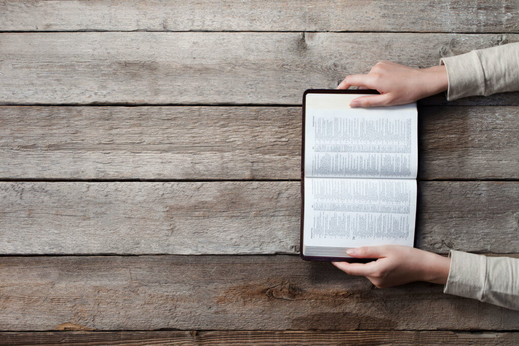 woman hands on bible. she is reading and praying over bible over wooden table